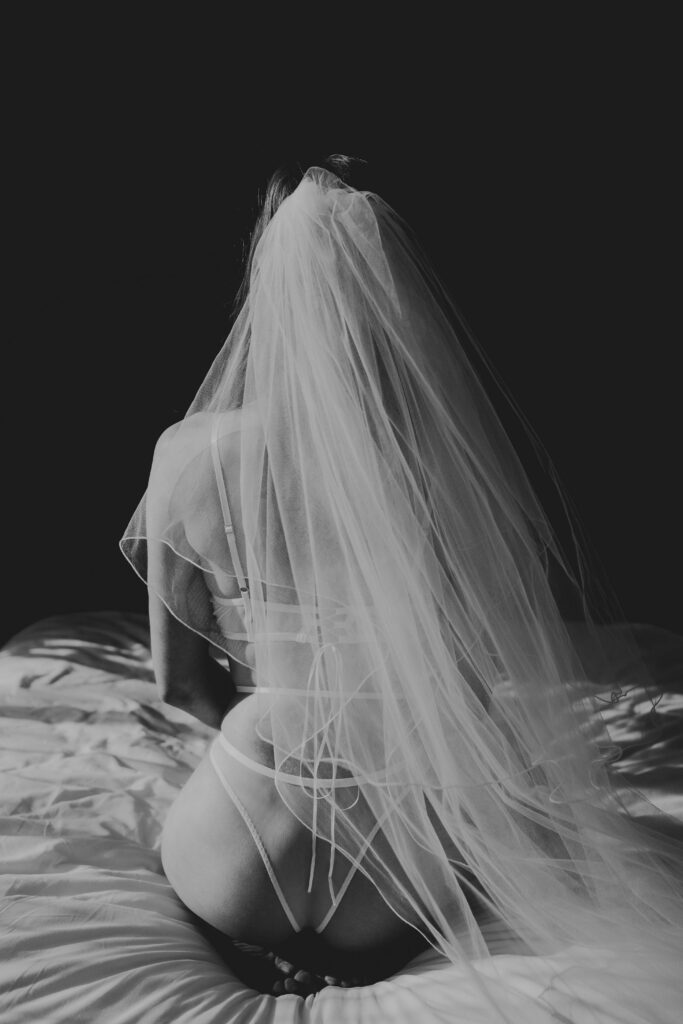 Bride tijdens een stijlvolle boudoir shoot voor haar bruiloft in een lichte, vrouwelijke setting”